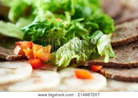Cropped close up of chopped salsd and red pepper on sliced assorted meat plate copyspace food pieces eatng tasty hungry restaurant gourmet delicacy concept.