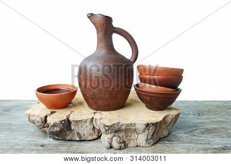 A Traditional Georgian Wine Jug And Clay Cups Filled With A Red Wine On The Wooden Table With Grapes