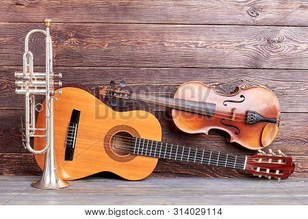 Musical Instruments Of Vintage Style. Trumpet, Acoustic Guitar And Violin On Wooden Background. Clas