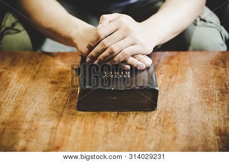 Spirituality And Religion, Hands Folded In Prayer On A Holy Bible In Church Concept For Faith.