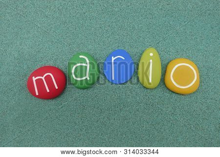 Mario, Masculine Given Name Composed With Multi Colored Stones Over Green Sand