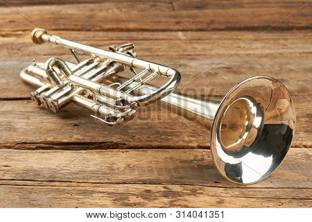 Rusty Trumpet On Old Wooden Surface. Antique Trumpet On Rustic Boards. Classical Jazzy Instrument.