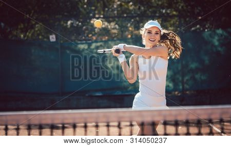 Woman forcefully playing tennis on court