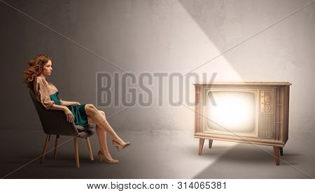 Elegant young lady watching to a vintage television