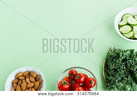 Vegetables And Nuts On A Light Green Background. Cherry Tomatoes, Cabbage Cale, Cucumbers And Almond