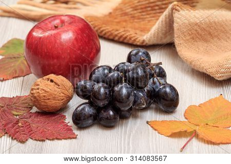 Grapes, Walnut, Apple And Dry Leaves In An Autumn Still Llife.