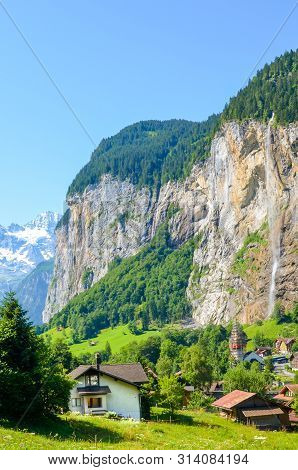 Vertical Photography Of Picturesque Village Lauterbrunnen In Swiss Alps. Famous Staubbach Falls In B