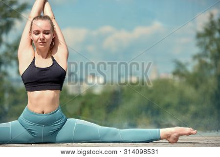 Beautiful Athletic Young Girl In Sportswear, Doing Exercises For Stretching On The Street, The Eleme