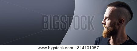 Banner With Free Copy Space For Text. Portrait. Profile Of A Young Man With A Red Beard On A Gray Ba