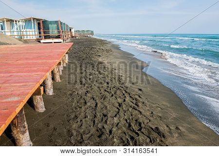 Beautiful Sea, The Black Sandy Beach And White And Blue Striped Beach Houses, Tyrrhenian Sea Near Ro