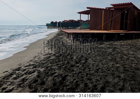 Beautiful Sea, The Black Sandy Beach And Beach Houses, Tyrrhenian Sea Near Roma, Italy