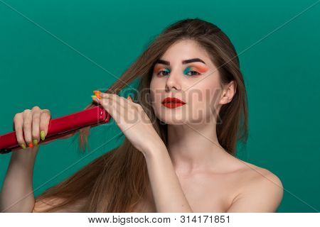 Portrait Of Beautiful Young Woman With Bright Color Make-up Doing Hair Style Herself With A Purple S