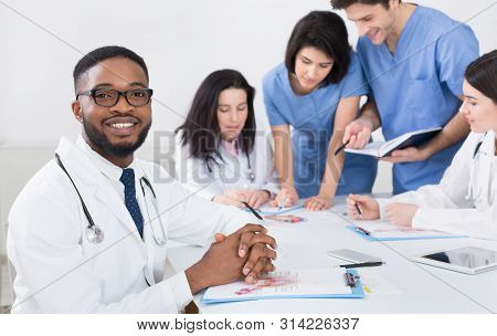 African-american Head Doctor. Practitioners And Interns At Meeting In Medical Office
