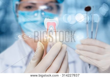 The Concept Of Dental Treatment. The Doctor Looks At The Model Of The Tooth.