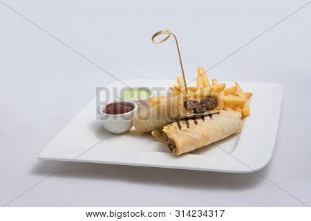 A Low Contrast Hero Shot Of A Beef Wrap Sandwich With Samurai & Alger Sauce And Fries On The Side, O