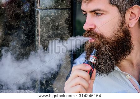 Man With Beard Breathe Out Smoke. Smoking Electronic Cigarette. Stress Relief Concept. Smoking Devic