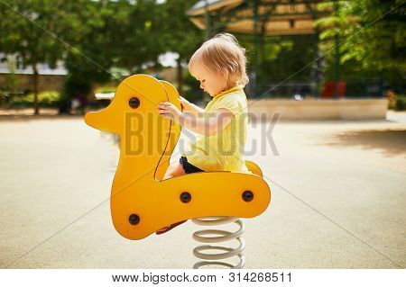 Adorable Toddler Girl Having Fun On Spring Rider On Playground. Outdoor Activities For Kids