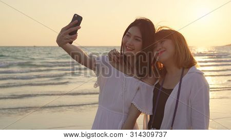 Young Asian Lesbian Couple Using Smartphone Taking Selfie Near Beach. Beautiful Women Lgbt Couple Ha