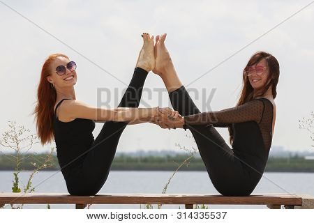 Two Young Women Doing Yoga At Nature. Fitness, Sport, Yoga And Healthy Lifestyle Concept - Group Of