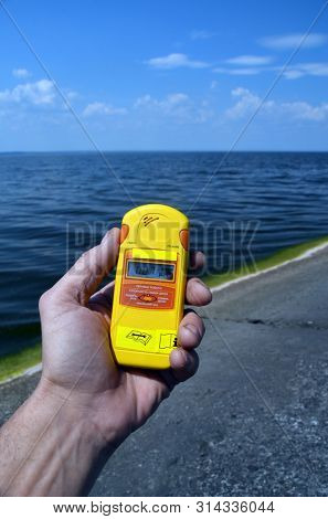 Geiger counter near storage pool near of hydroelectric station. After Chernobyl disaster - collection active sediments.The radiometer gives readings in micro-Sieverts. July 29, 2019.Kiev ,Ukraine