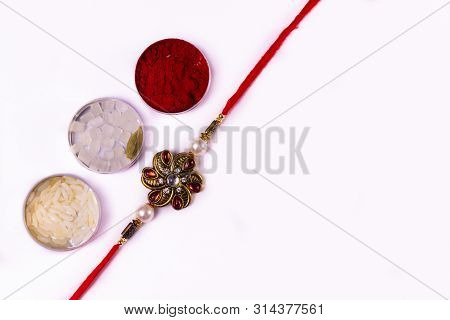 Indian Festival  - Raksha Bandhan Concept - An Elegant Rakhi With Rice Grains, Kumkum, Sugar Rock An