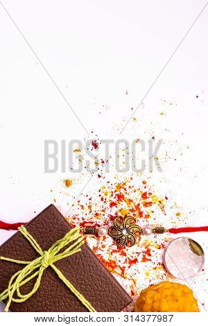 Indian Festival - Elegant Rakhi With Scattered Rice, Kumkum And Haldi On White Background With Brown