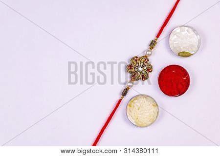 Indian Festival Raksha Bandhan Background With An Elegant Rakhi And Rice Grains, Kumkum, Sugar Rock 