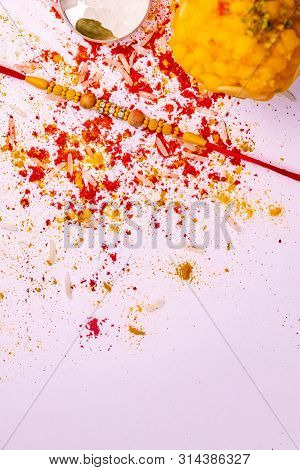 Raksha Bandhan - Elegant Rakhi, Sweet With Spread Rice Grains, Kumkum, And Haldi On White Background