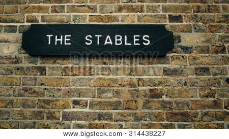 Wooden Sign For The Stables On Brick Wall