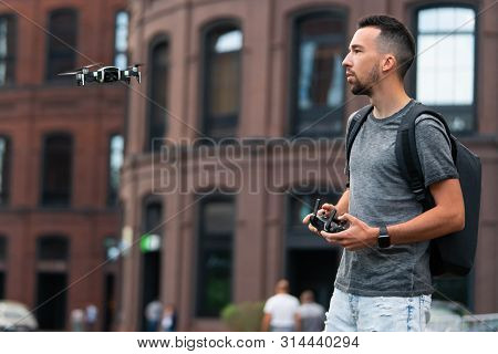 Young Handsome Man Launching Drone Quadcopter At Urban Background.