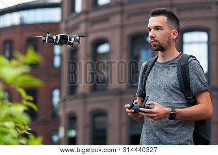 Young Handsome Man Launching Drone Quadcopter At Urban Background.