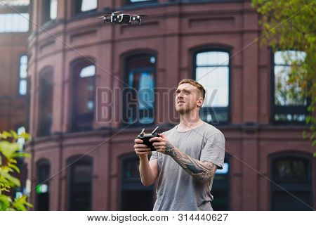 Young Handsome Man Launching Drone Quadcopter At Urban Background.