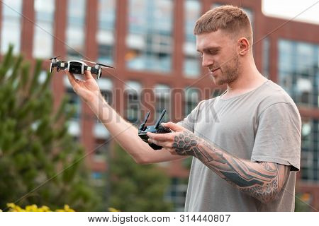 Young Handsome Man Launching Drone Quadcopter At Urban Background.