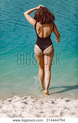 Woman In Black Swimsuit At Sand Beach View From Behind Summer Vacation