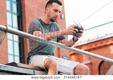 Young Handsome Man With Drone Quadcopter Joystick Controller At Urban Background.