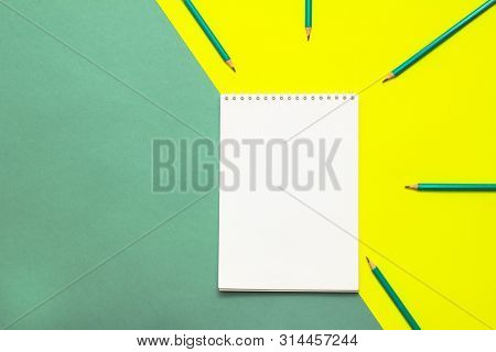 White Wideopen Blank Clean Notepad Page And Green Pencils On Yellow-green Table.