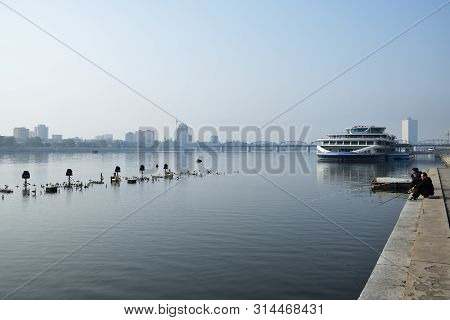 Pyongyang, North Korea - May 1, 2019: Two Fishermen Catch A Fish On Waterfront On  Kim Il Sung Squar