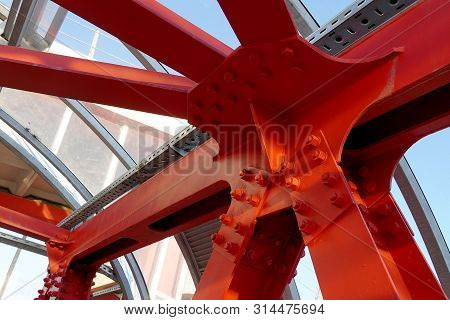 Red Iron Beams Bolted On. Angular Connection Of Several Iron Beams In One Place Close Up.