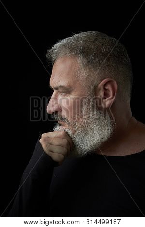 Portrait Of A Brutal Gray Haired Man With A Gray Lush Beard And Strict Face On A Black Background, S
