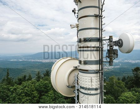 Powerful Tall Lte 5g Antenna Tower With Green Forest Hills And Mountains In Background