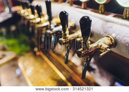 Close Up Of Beer Taps In Row. Metallic Equipment For Bars And Mini Brewerys. Concept Of Modern Equip