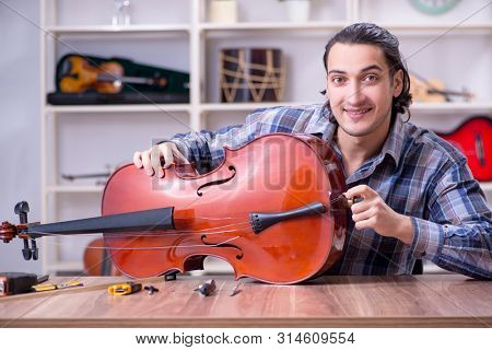 Young handsome repairman repairing cello