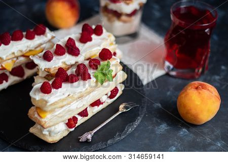 Dessert Milfey. Strips Of Puff Pastry With Curd Cream Raspberry Berries And Peach Slices. In The Bac
