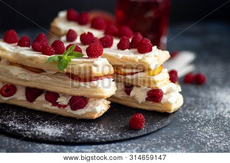 Dessert Milfey. Strips Of Puff Pastry With Curd Cream Raspberry Berries And Peach Slices. In The Bac
