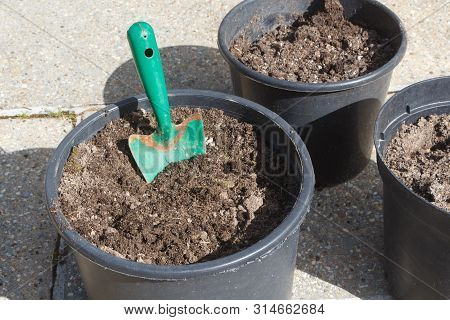 Plastic Flowerpot With Loam And Gardening Trowel