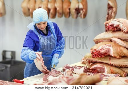 Cutting Meat In Slaughterhouse. Butcher Cutting Pork At The Meat Manufacturing.