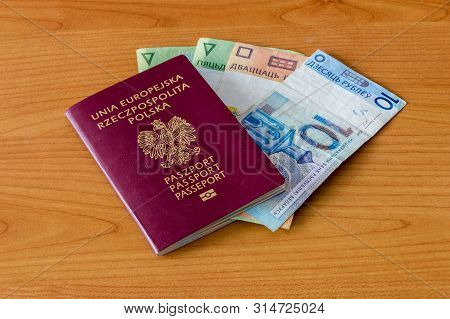 Polish Biometric Passport And Belarusian Currency On Wooden Table.