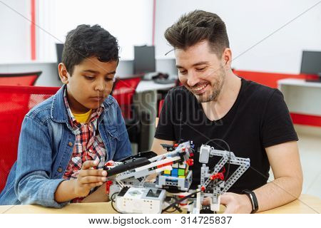 Mixed Racial Group Of School Children Controlling Robotic Machine With Remote Control Together Teach
