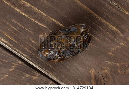 One Whole Dried Brown Date Medjool Flatlay On Brown Wood