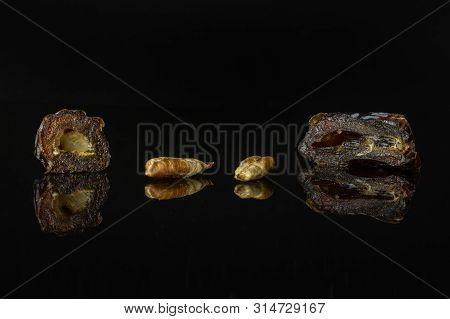Group Of Two Halves Two Pieces Of Dried Brown Date Medjool Isolated On Black Glass